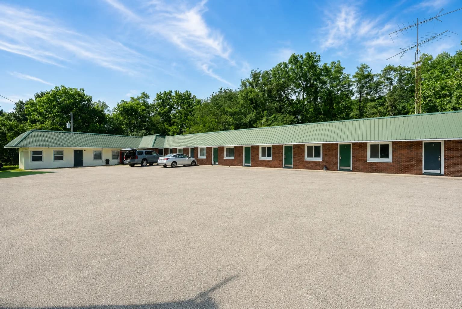 Brick motel building with a green metal roof under a blue sky